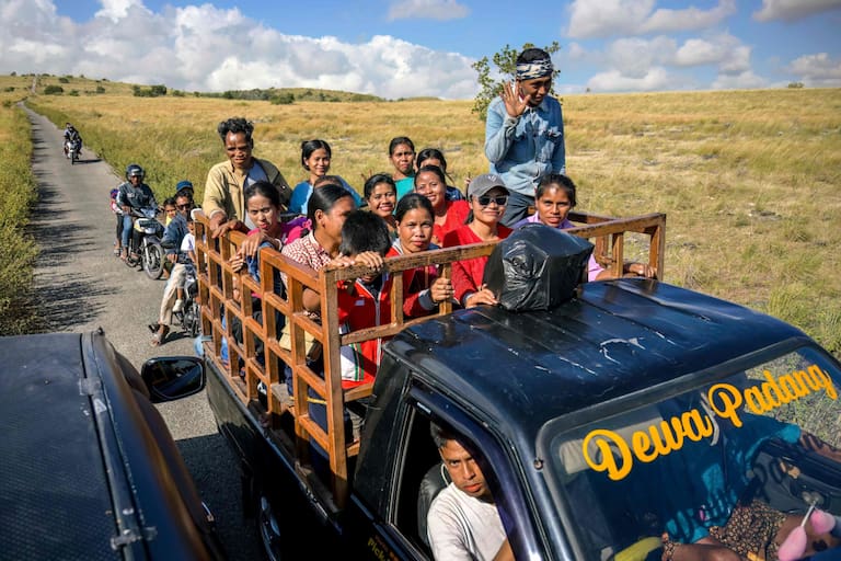 This photo taken on June 23, 2026 shows villagers riding a truck along a road at Tanggedu village in East Sumba, East Nusa Tenggara. Two hours from the tourist beaches of Bali, slavery is alive and well on the Indonesian island of Sumba, where people are still being born into bondage. Eight of out 10 of Sumba's population of 685,000 people are Christian but its older "marapu" belief system, that blends animism and ancestor worship, has deep roots. It divides society into three castes, "the nobles, called 'maramba' -- often large landowners -- ordinary people called 'kabihu' and the slaves/servants, the atas," said rights activist Martha Hebi, author of several studies on the subject. (Photo by BAY ISMOYO / AFP) / To go with Indonesia-Sumba-slavery, SPECIAL REPORT by Eric Bernaudeau
