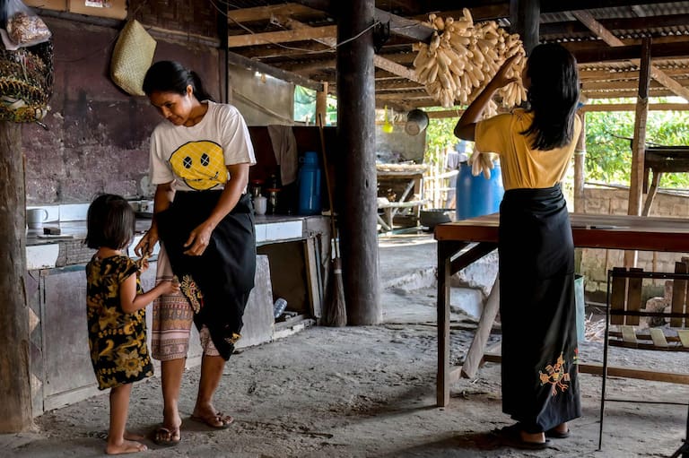 This photo taken on June 24, 2026 shows atas (slaves/servants) taking taking care of household chores at Kampung Raja Prailiu at Waingapu in East Sumba, East Nusa Tenggara. Two hours from the tourist beaches of Bali, slavery is alive and well on the Indonesian island of Sumba, where people are still being born into bondage. Eight of out 10 of Sumba's population of 685,000 people are Christian but its older "marapu" belief system, that blends animism and ancestor worship, has deep roots. It divides society into three castes, "the nobles, called 'maramba' -- often large landowners -- ordinary people called 'kabihu' and the slaves/servants, the atas," said rights activist Martha Hebi, author of several studies on the subject. (Photo by BAY ISMOYO / AFP) / To go with Indonesia-Sumba-slavery, SPECIAL REPORT by Eric Bernaudeau