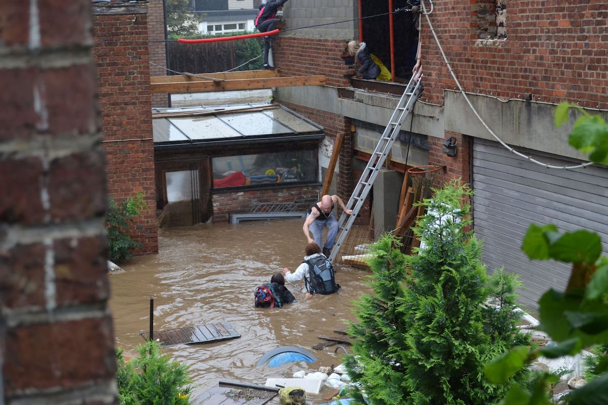 This photograph taken on July 15, 2021 shows a Belgian family being helped to safety after their house was engulfed by floodwaters from the river Vesdre in Trooz. - One month after huge storms battered northwestern Europe and forced an unprecedented wave of floodwater through densely populated valleys, Belgian residents are still in shock. The government of Wallonia has collected 155,000 tonnes of debris but red-brick industrial villages are still cluttered by smashed cars, uprooted trees and furniture ruined by mud and heating oil. (Photo by Charles CLESSENS / AFP)