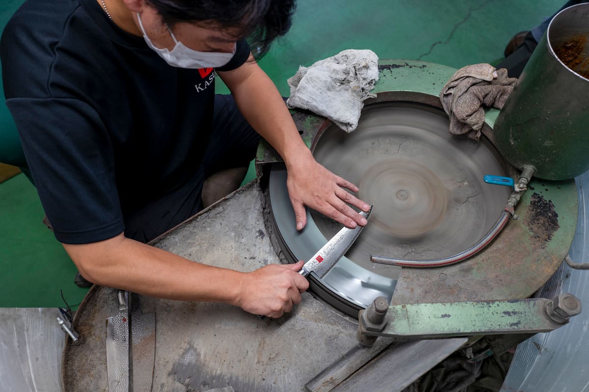 This picture taken on September 2, 2022 shows a worker finishing a knife with a rotating whetstone in the final process at a factory of Sumikama Cutlery in Seki, Gifu prefecture. - In a Japanese city once famous for forging samurai swords, craftsmen sharpen and polish kitchen knives, but even at full tilt their small factory can't keep up with global demand. The export value of knives and other bladed tools like scissors hit a record high in Japan last year, partly thanks to a home-cooking boom sparked by the pandemic. (Photo by Kazuhiro NOGI / AFP) / TO GO WITH AFP STORY Japan-lifestyle-culture-craft-knives by Natsuko FUKUE