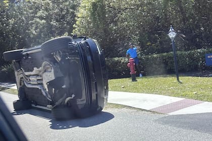 Tiger Woods, parado a un costado de su vehículo volcado en Jupiter Island, Florida, el viernes 27 de marzo de 2026. (Foto AP/Jason Oteri)