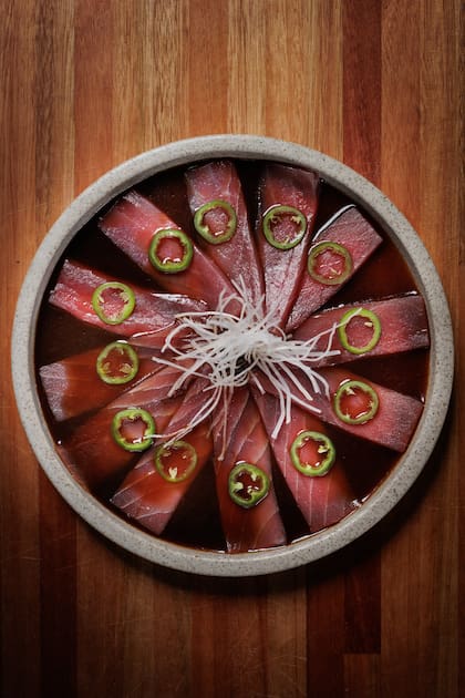 Tiradito Tuna Truffle: láminas de atún fresco con jalapeño, nabo y ponzu trufada. El plato combina la precisión del corte japonés con la intensidad de los aderezos peruanos.