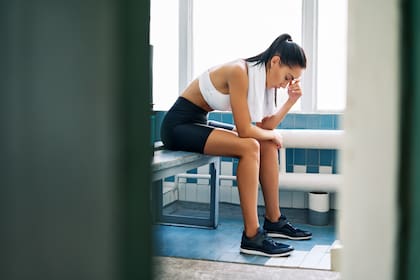 Tired fit woman with a towel in the locker room after hard workout. Stress, sport, failure concept