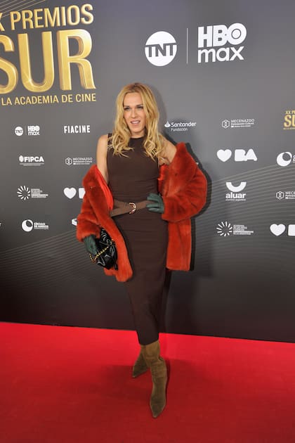 Toda la onda. Mariana Genesio Peña desfiló por la alfombra roja con un vestido chocolate de largo midi y botas de gamuza. Su abrigo de piel en color naranja y sus guantes de cuero en un verde azulado se llevaron todas las miradas