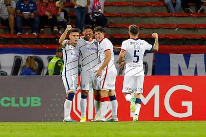 Todos abrazan a Bareiro, autor del gol para el triunfo de San Lorenzo en Medellín; un valioso éxito que le deja la mitad de la serie en el bolsillo
