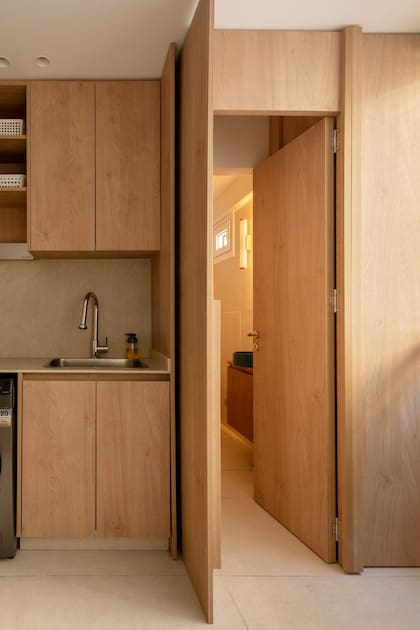 “Todos los espacios tienen ventana y buena iluminación, porque los vecinos están lejos. No hay nada que les haga sombra”. Muebles de cocina y lavadero oculto en melamina ‘Roble Kendal’ natural (Egger).