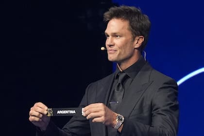 Tom Brady, figura del fútbol estadounidense (NFL) sostiene el papel con el nombre de Argentina durante el sorteo de la fase de grupos del Mundial