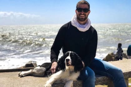 Tomás Caldiroli Stankievich junto a su perra Cleo, con el océano atlántico de fondo, en Mar del Plata