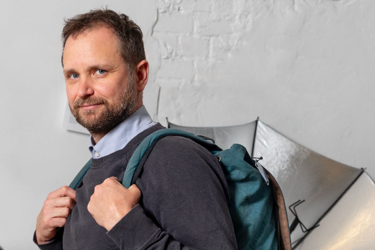 Tomás Saraceno en su estudio de Berlín, con la mochila que permite transportar "esculturas solares" y un paraguas diseñado para cocinar con energía solar