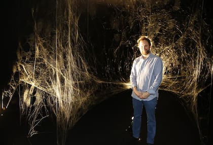 Tomás Saraceno junto a la tela construida por miles de arañas en el Moderno