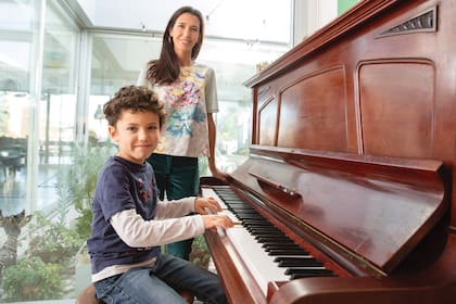 Tomás toca el piano ante la mirada atenta de su mamá.