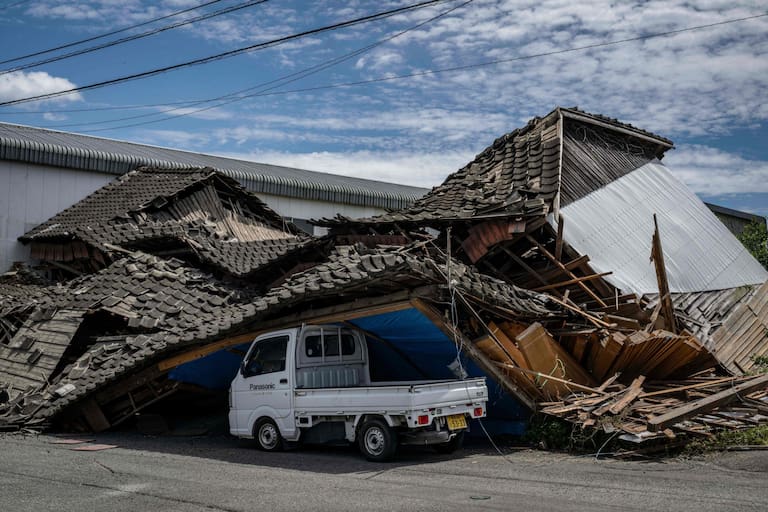 TOPSHOT - A house is seen collapsed onto a car in Yatsushiro, Kumamoto prefecture on July 29, 2026, after an earthquake struck southwestern Japan the previous day. (Photo by Yuichi YAMAZAKI / AFP)