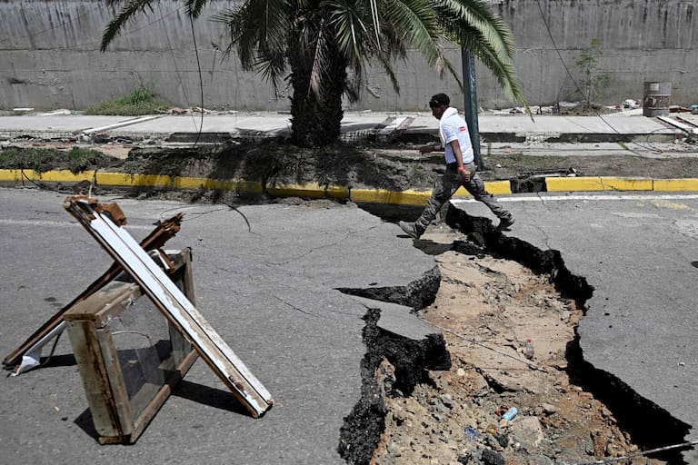 TOPSHOT - A man walks in a cracked street following a twin earthquake, in Los Corales, La Guaira state, about 38 km northwest of Caracas, on June 25, 2026. The death toll from twin quakes, measured at magnitudes 7.2 and 7.5, has risen to at least 188, with more than 1,520 others injured, top lawmaker Jorge Rodriguez reported, while residents continue searching for missing relatives. (Photo by Federico PARRA / AFP)
