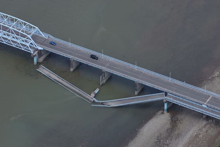 TOPSHOT - Cars drive on the partially colapsed Ueyanagi Bridge in Yatsushiro, Kumamoto Prefecture, on July 29, 2026, after an earthquake struck southwestern Japan the previous day. (Photo by JIJI PRESS / AFP) / Japan OUT