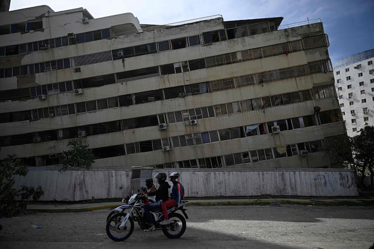 TOPSHOT - Locals ride a motorbike past a damaged building following a twin earthquake in Caraballeda, La Guaira state, about 40 km northeast of Caracas, on June 25, 2026. The death toll from twin quakes, measured at magnitudes 7.2 and 7.5, has risen to at least 188, with more than 1,520 others injured, top lawmaker Jorge Rodriguez reported, while residents continue searching for missing relatives. (Photo by Federico PARRA / AFP)