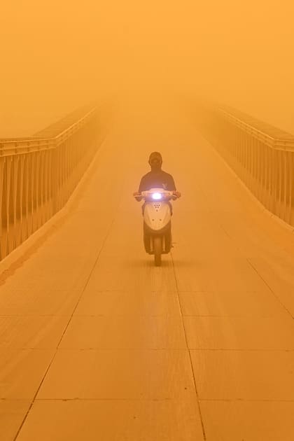Un hombre conduce un scooter a lo largo de un puente en la ciudad de Nasiriyah, en el sur de Irak