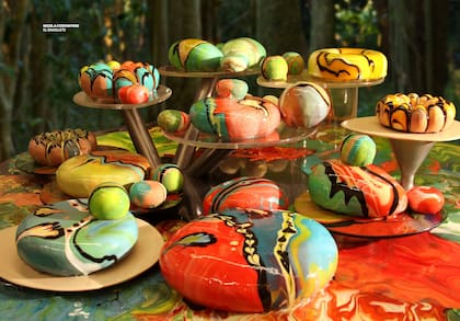 "Tortas Costantinopla", la artista trabaja con tortas heladas cubiertas mediante la técnica francesa del mirror glaze (baño espejo), donde el color fluye sobre la superficie congelada creando composiciones abstractas e irrepetibles antes de solidificarse
