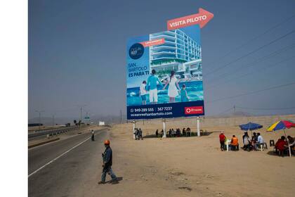 Trabajadores almuerzan a la sombra de un gigantesco cartel de publicidad en un vecindario pobre de la zona sur de Lima