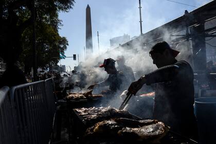 Trabajadores asan carne en un puesto durante un campeonato de parrilleros el domingo 14 de agosto de 2022, en Buenos Aires, Argentina. (AP Foto/Rodrigo Abd)