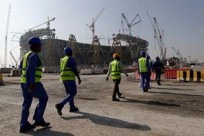 Trabajadores caminan afuera del Estadio Lusail, uno de los estadios del Mundial de Qatar 2022, el 20 de diciembre del 2019 (AP Foto/Hassan Ammar, Archivo)