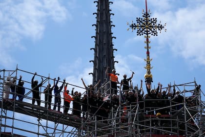 Trabajadores celebraron la instalación de la Croix du Chevet de la catedral de Notre Dame de París, derecha, el viernes 24 de mayo de 2024, en París. (AP Foto/Thibault Camus)