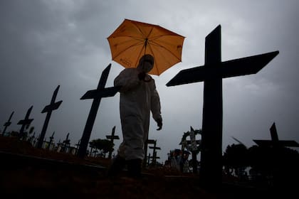 Trabajadores con protección especial caminan junto a tumbas de víctimas del Covid en el cementerio Nossa Senhora Aparecida de Manaos