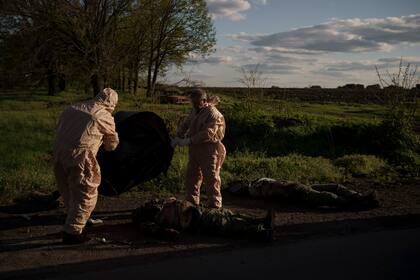 Trabajadores de emergencias se preparan para sacar los cadáveres de soldados rusos de la aldea de Vilkhivka, recuperada recientemente por las fuerzas ucranianas, cerca de Járkiv, Ucrania, el 9 de mayo de 2022. (AP Foto/Felipe Dana)
