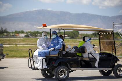 Trabajadores de la salud se alejan en un móvil después de controlar la temperatura corporal de los haitianos deportados que llegan de los Estados Unidos, en el Aeropuerto Internacional Toussaint Louverture en Port-au-Prince, Haití