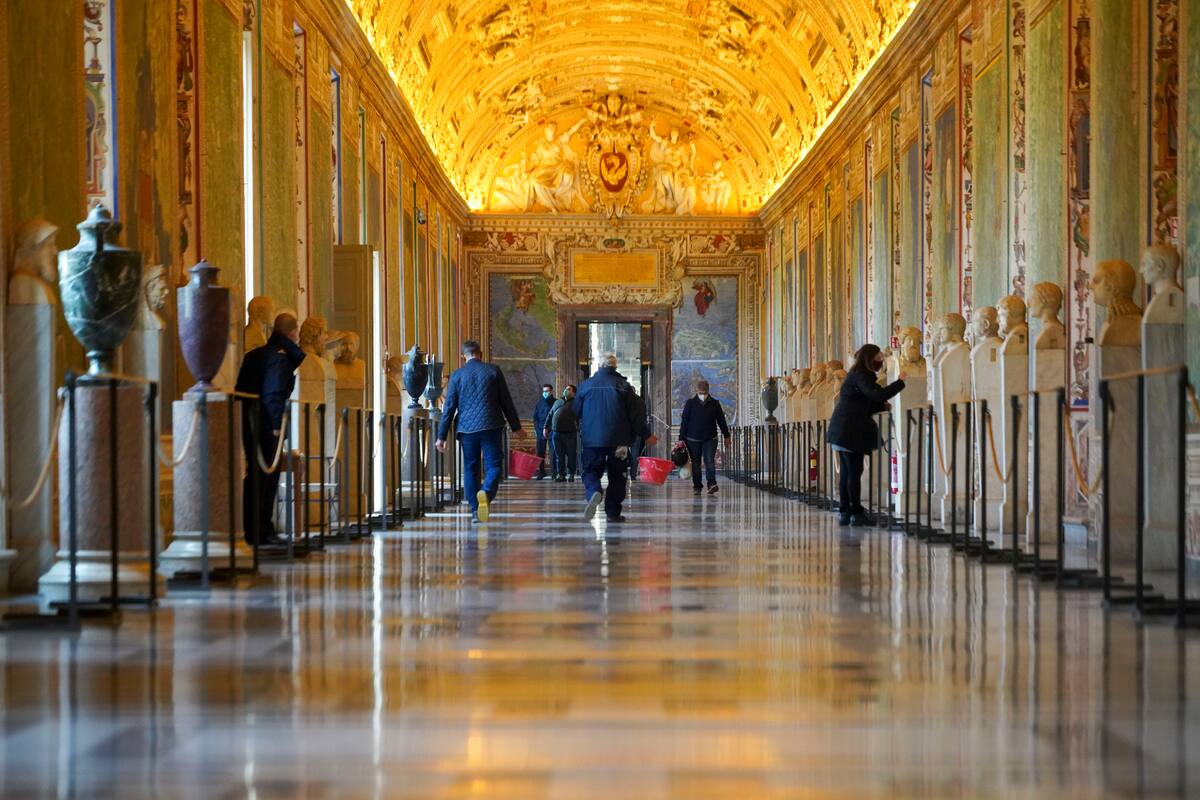 Trabajadores de museo caminan por un pasillo de los Museos Vaticanos antes de la apertura, en el Vaticano, el lunes 1 de febrero de 2021