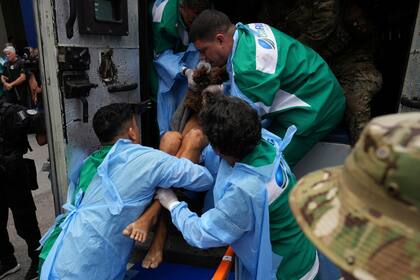 Trabajadores del Hospital Getulio Vargas retiran a una persona herida de un camión policial tras resultar herida