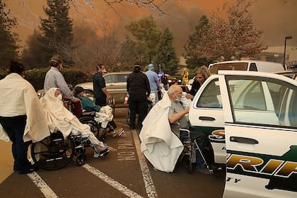 Trabajadores del hospital y socorristas evacuan a los pacientes del hospital Feather River en Paradise, California.