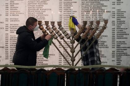 Trabajadores del Parlamento polaco limpian una menorá después de que un legislador de extrema derecha agarrara un extintor y apagara las velas, alterando una celebración de la fiesta judía de Hanukkah, en Varsovia, Polonia, el martes 12 de diciembre de 2023. (AP Foto/Czarek Sokolowski)