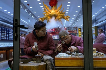 Trabajadores fabrican joyería de playa en una tienda en Beijing