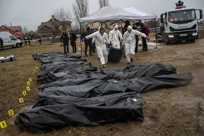 Trabajadores forenses trasladar el cuerpo de un civil asesinado durante la guerra con Rusia tras sacarlo de una fosa común en Kiev, Ucrania, el 8 de abril de 2022. (AP Foto/Rodrigo Abd)