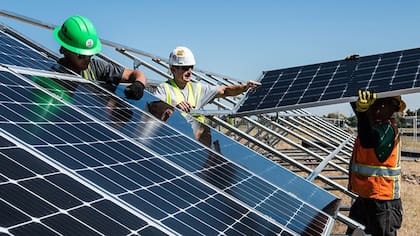 Trabajadores instalan paneles solares en un techo