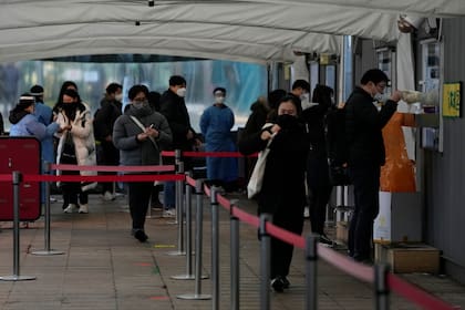 Trabajadores médicos en cabinas toman muestras nasales de la gente en un centro temporal de pruebas diagnósticas, el martes 25 de enero de 2022, en Seúl, Corea del Sur. (AP Foto/Ahn Young-joon)