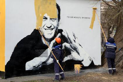 Trabajadores municipales pintan sobre una imagen del encarcelado líder opositor ruso Alexei Navalny en San Petersburgo, Rusia, el 28 de abril de 2021. (AP Foto/Valentin Egorshin, archivo)