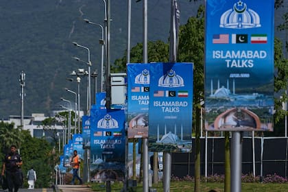 Trabajadores pasan junto a vallas publicitarias cerca del Hotel Serena antes de la segunda ronda de negociaciones entre EEUU e Irán, en Islamabad, Pakistán, el lunes 20 de abril de 2026. (Foto AP/Anjum Naveed)