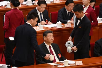 Trabajadores reponen las tazas de té del presidente chino Xi Jinping durante la sesión de apertura del Congreso Nacional del Pueblo (NPC) en el Gran Salón del Pueblo en Pekín el 5 de marzo de 2024.