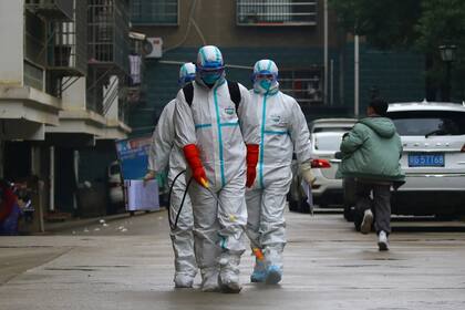 Trabajadores sanitarios desinfectan las calles en Wuhan