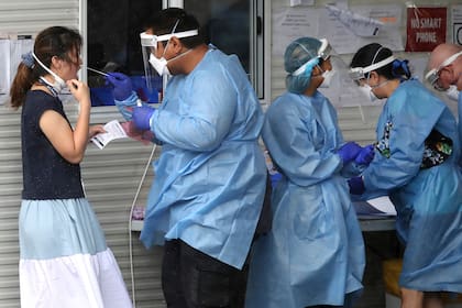 Trabajadores sanitarios, en un centro donde se realizan pruebas de detección del COVID-19, en Brisbane, Australia, el 7 de enero de 2022. (Jono Searle/AAP Image vía AP)