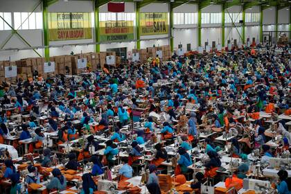 Trabajadores sentados en sus puestos en una fábrica propiedad de PT Eksonindo Multi Product Industry, fabricante de prendas de vestir y bolsos, en Bandung, provincia de Java Occidental, Indonesia, 11 de julio de 2024. (AP Foto/Achmad Ibrahim)