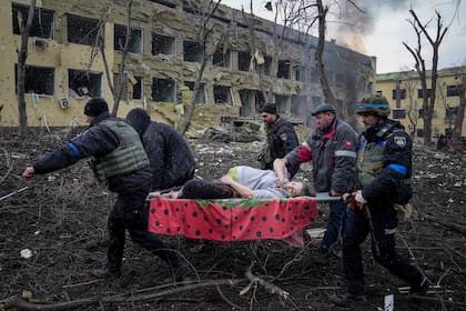 Trabajadores y voluntarios ucranianos de emergencia trasladan a una mujer embarazada entre los restos de un hospital de maternidad dañado por proyectiles en Mariúpol, Ucrania, el miércoles 9 de marzo de 2022. (AP Foto/Evgeniy Maloletka)