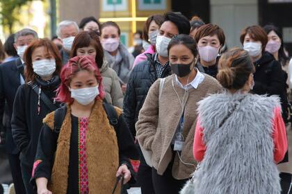 Transeúntes, con barbijo para protegerse del coronavirus, caminan por una calle en Tokio