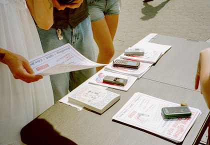 Transeúntes observan una mesa que contiene el libro de August Lamm, No necesitas un teléfono inteligente, además de teléfonos móviles analógicos y folletos (Casey Steffens/The New York Times)