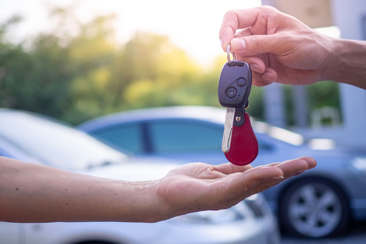 Transportation and ownership concept customer and salesman with car key outside.