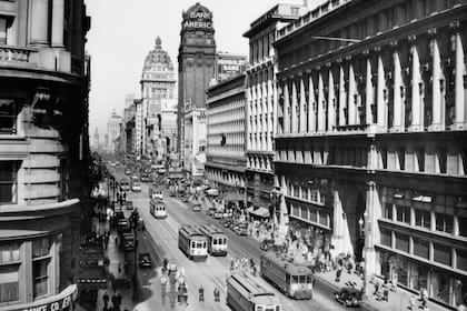 Tranvías en movimiento, autos, edificios comerciales y carteles luminosos en Market Street en San Francisco