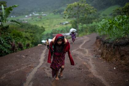 Tras intensas lluvias, una niña carga madera para cocinar en el asentamiento de Nuevo Quejá, Guatemala, el lunes 5 de julio de 2021. Los sobrevivientes de un alud de lodo provocado por el huracán Eta, que sepultó su pueblo, Quejá, en noviembre de 2020, se quedaron desubicados y desplazados en un endeble asentamiento. (AP Foto/Rodrigo Abd)
