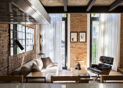 Tras la antigua fachada de estilo francés en el loft se armonizan la impronta industrial, un cuidado trabajo de las maderas, clásicos del diseño contemporáneo y secciones de ladrillo original.
