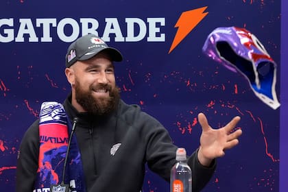 Travis Kelce, tight end de los Chiefs de Kansas City, atrapa una máscara mientras participa en la noche de apertura del Super Bowl 58, en Las Vegas